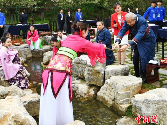 來自海內外的書法家身著晉服，在曲水邊品酒、賦詩、揮毫。